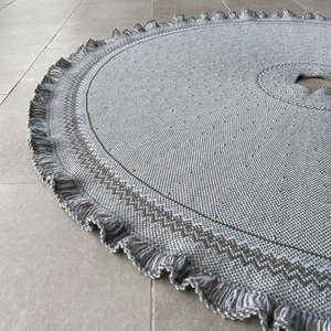 Detailed view of grey and white knitted Christmas tree skirt with decorative fringe edges