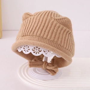 Dettaglio cappello in maglia beige per neonati con orecchie d'orso e fiocco decorativo