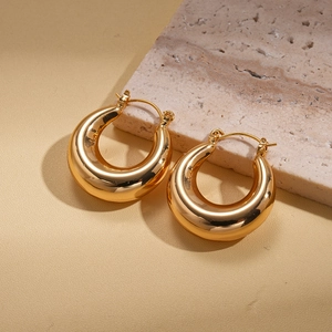 Minimalist gold geometric hoop earrings with polished finish on a stone display