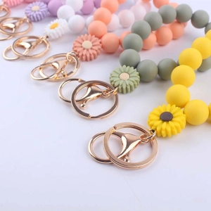 Colorful silicone beaded daisy bracelet keychain with golden ring in various pastel tones