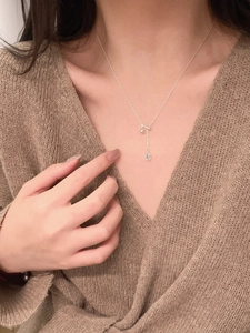 Detail of silver Y-shaped S925 necklace with blue teardrop sapphire pendant on model