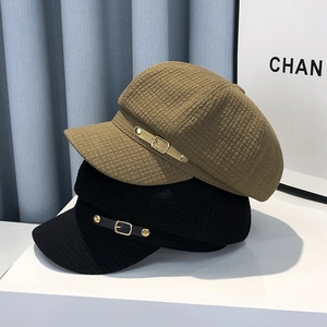 Detail of khaki and black newsboy hats showing waffle fabric and metal buckle trim