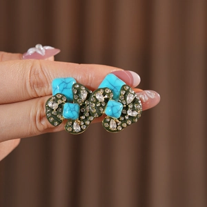 Macro shot of vintage irregular earrings with green enamel and sparkling rhinestones