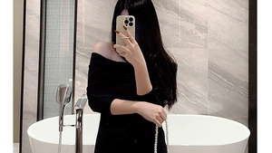 Detailansicht einer weißen Abendhandtasche mit Perlenkette zu einem schwarzen Kleid