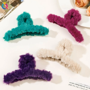 Close-up of four plush hair claw clips in cyan, rose pink, deep purple, and cream colors