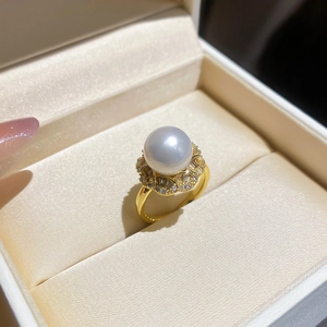 Macro detail of luxury pearl flower ring with zircon pavé on golden metallic band