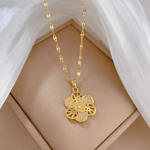 Detail of a gold flower necklace with white zircons on a light brown jewelry display