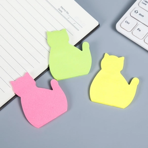 Flat lay of cute cat-shaped sticky notes in green, yellow, and pink on a desk