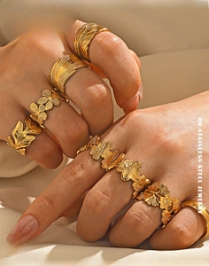 Detail view of stacked stainless steel rings with leaf, flower, and feather patterns