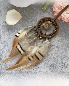 Detailed close-up of handmade dreamcatcher pendant with tiger eye stone and natural feathers