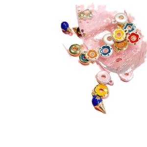 Colorful enamel ice cream and donut metal charms scattered on a white surface