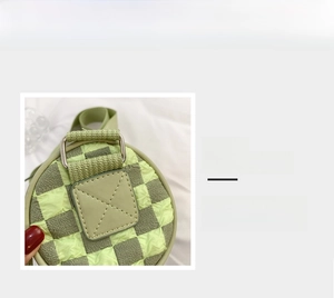 Detail of green checkered bubble textured cylinder bag with silver metal ring buckle
