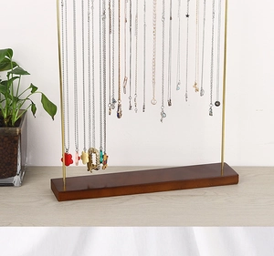 Detailed view of the sleek gold metal jewelry stand with a stable solid wood base
