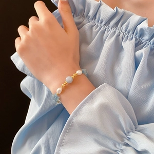 Vue détaillée du bracelet en perles et aigues-marines avec accents dorés au poignet