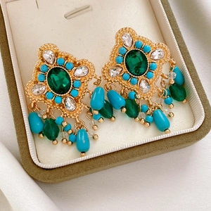 Gros plan de boucles d'oreilles vintage avec pierres vertes et glands de perles dans un écrin à bijoux
