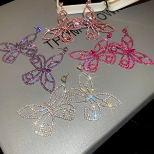 Macro detail of butterfly earrings with hollow alloy frames and sparkling rhinestones