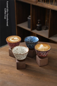 Artistic close-up of funnel-shaped stoneware coffee mugs with rustic kiln-glaze and square bases