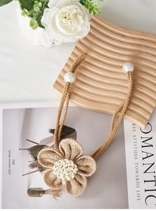Detail of handmade jute flower curtain tieback with natural fiber texture and pearl accents