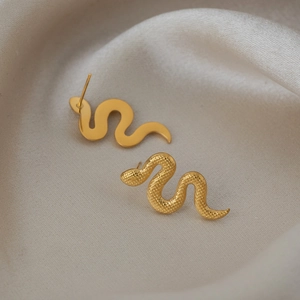 Détail de boucles d'oreilles serpent dorées avec finitions polies et texturées fines
