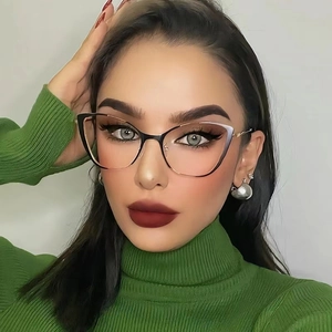 Close-up of black and gold cat-eye metal glasses frame worn by a model in a green sweater