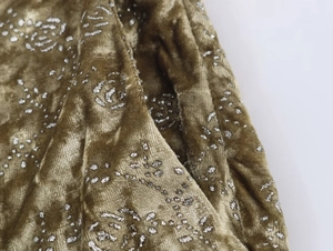 Detail view of bronze green velvet fabric featuring silver glitter rose floral patterns