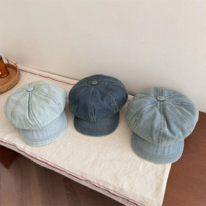 Tre berretti in denim nelle tonalità azzurro, medio e blu scuro su un panno di lino