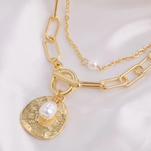 Detail of gold double-layer chain necklace with irregular pearls and toggle clasp