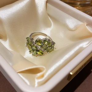 Macro view of olive green zircon ring with multi-stone inlay in a premium jewelry box