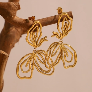 Detail of 18K gold-plated irregular lava design earring on a rustic wooden branch