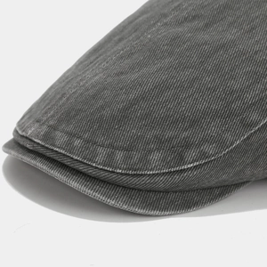 Close-up of durable dark grey washed denim fabric and double-stitched brim on flat cap