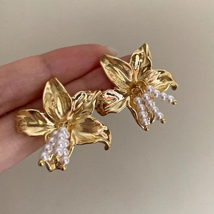 Close-up of golden metal flower earrings with delicate pearl center details