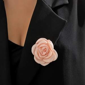 Close-up of a light pink fabric rose brooch pinned on a black suit lapel detail
