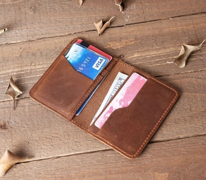 Flat lay of vintage brown leather card holder with multiple slots on a rustic wooden desk