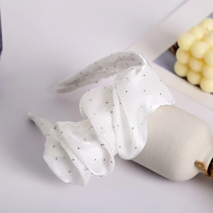 Close-up of white satin headband with silver rhinestones and ruffled texture detail