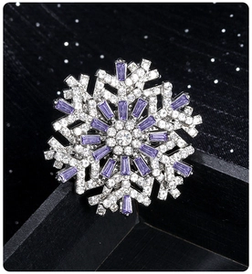 Detailed view of a silver snowflake brooch with sparkling clear and purple crystals