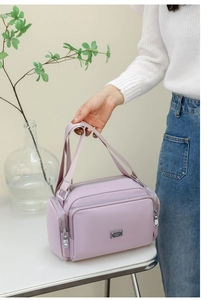 Detalle de un bolso bandolera de nailon lavanda con varios bolsillos con cremallera