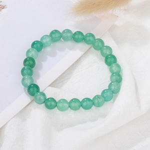 Detailed view of green round beads bracelet on white fabric with natural dry hay accents