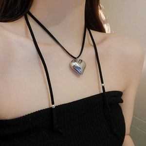 Close-up of a polished silver heart pendant on a black leather choker necklace