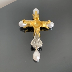 Detailed back view of a vintage cross brooch with pins, gold and silver metal tones