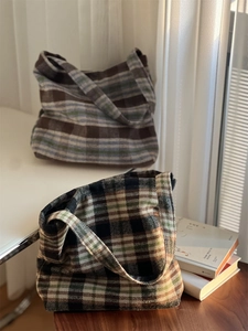 Gros plan de deux sacs portés épaule en laine à carreaux marron et gris sur table