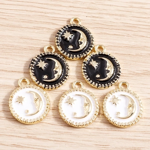 6 pieces of star and moon round enamel charms with gold frames on a wooden background