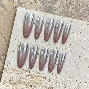 Long almond chrome gradient press-on nails with silver mirror finish on travertine stone