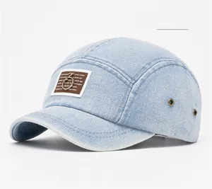 Detail of light blue washed denim baseball cap featuring a brown faux leather patch and metal ring