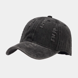 Close-up of distressed brim details on a washed black cotton twill baseball cap