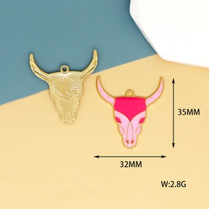 Detail view of bull head charms in gold metal and pink enamel for DIY jewelry making