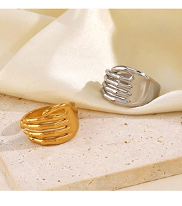 Detailed view of gold and silver hugging hands rings on a textured stone and silk surface