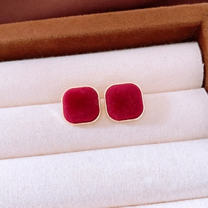 Close-up of vintage red velvet stud earrings with gold border on jewelry cushion