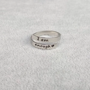 Macro detail of 'I am enough' engraving and heart on adjustable stainless steel ring