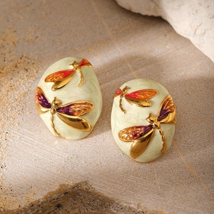 Detailed macro view of oval dragonfly earrings with colorful enamel on a stone base