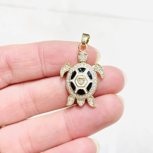 Close-up of turtle pendant with black and white enamel shell and clear zircon stones